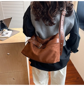 Détail de la bandoulière réglable et de la boucle sur le sac fourre-tout en daim brun