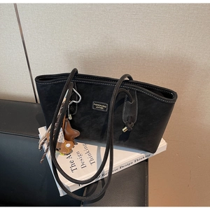 Détail d'un sac cabas en cuir noir avec plaque logo et charmant pendentif d'ours brun