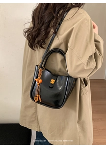 Gros plan du sac seau en cuir noir avec fermoir doré et pendentif rétro à perles