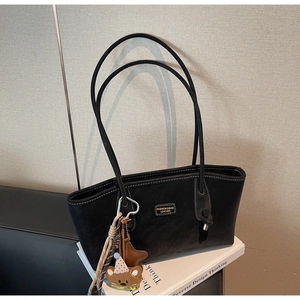 Détail du sac cabas en cuir noir avec fines bretelles et charmant petit ours suspendu