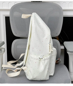 Detailed view of cream canvas backpack with polka dots and functional drawstring side pocket