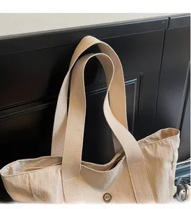 Detail of reinforced woven handles and stitching on beige nylon tote bag