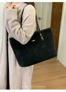 Grand sac cabas noir en daim avec détails dorés porté par un mannequin à l'épaule