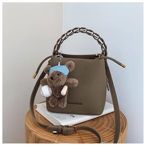 Detail of coffee brown lychee leather bucket bag with cute plush bear charm on books