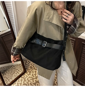 Grand sac bandoulière noir mat avec boucle argentée porté par un mannequin chic