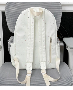 Detailed back view of white polka dot backpack with hidden zipper pocket and padded straps