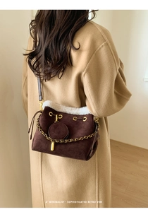 Detail of dark brown matte bucket bag with white fleece trim and gold chain strap