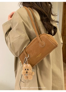 Detail of vintage brown faux suede shoulder bag with white contrast stitching and puppy charm