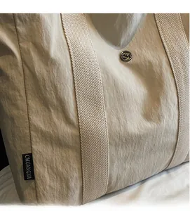 Detail of nylon tote bag fabric texture with black brand label and metallic snap button