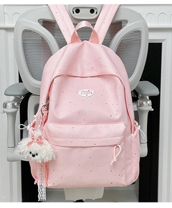 Detail view of pink polka dot backpack with water-resistant fabric and plush dog charm