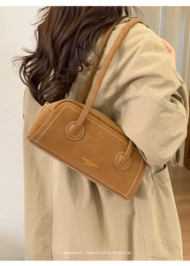Detail of vintage brown leather baguette bag with gold lettering and contrast stitching