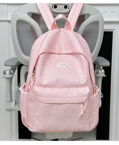 Detail of pink polka dot backpack showing the front pocket and embroidered brand logo