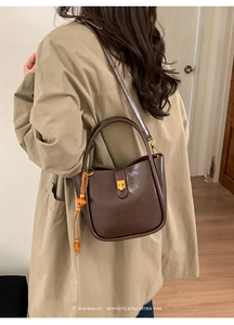 Détail du sac seau vintage marron foncé avec boucle dorée et accessoire perlé