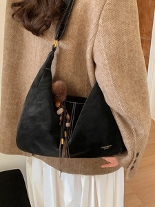 Minimalist black crescent shoulder bag with brown pompom and fringe tassel charm