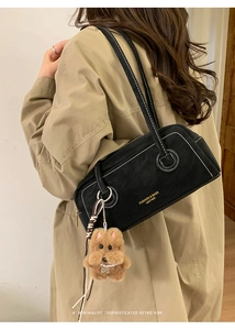 Detail of black Boston underarm bag with white stitching and plush dog charm