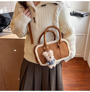 Détail d'un sac Boston mat marron avec bordure en peau lainée et pendentif ours en peluche
