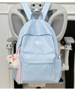 Detail of light blue polka dot backpack featuring side pocket and plush dog charm
