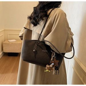 Détail du sac cabas en daim marron foncé avec surpiqûres et charmant petit ours en peluche