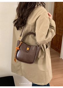 Détail d'un sac seau rétro en cuir marron foncé avec pompon de perles en bois orange