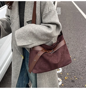 Détail du sac hobo en daim bordeaux mat avec bandoulière en cuir brun et boucle