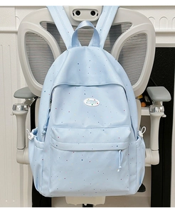 Close-up of light blue polka dot backpack showing waterproof nylon texture and side pocket