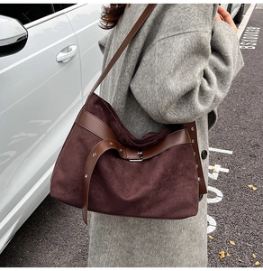 Détail d'un grand sac hobo en daim marron avec bandoulières en cuir sur un modèle