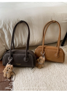 Detail view of retro leather underarm bags in brown tones with cute plush bear charms