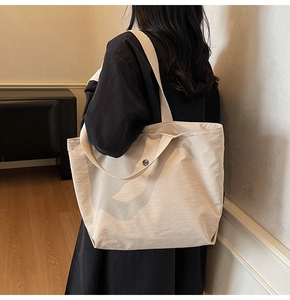 Detail view of cream canvas tote bag featuring silver magnetic closure and woven shoulder strap