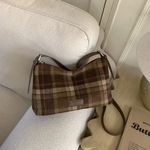 Détail d'un sac cabas à carreaux marron avec étiquette mode sur un canapé doux