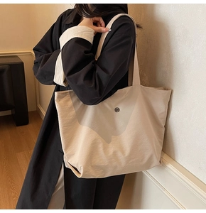 Detail of minimalist beige canvas tote bag with metal button shown in interior setting