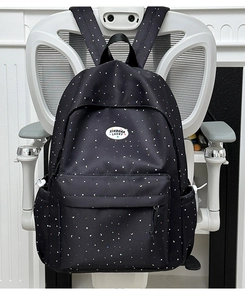 Detailed view of polka dot backpack with moon and star patterns hanging on a chair