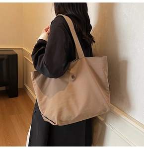 Detail of minimalist khaki canvas tote bag on model showing large capacity and strap