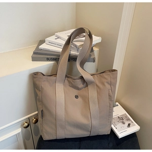 Detailed view of casual beige tote bag with nylon texture and side pocket on books