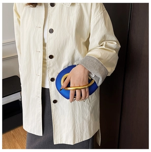 Close-up of electric blue acrylic clutch bag with chunky gold metal ring handle