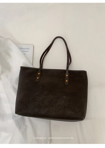 Detailed view of dark coffee tote bag with vintage texture and gold rivet studs