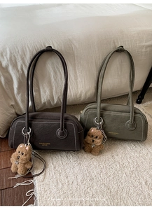 Detailed view of structured underarm bags with white contrast stitching and plush charms