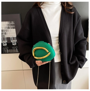 Detail of green teardrop evening bag with gold horseshoe handle and chain strap