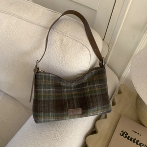 Détail d'un sac cabas à carreaux vintage avec bandoulière en cuir brun et laine
