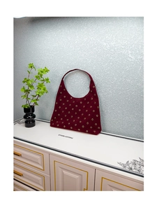 Detailed macro view of dark burgundy suede hobo bag with uniform golden metal eyelets