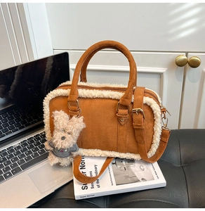 Détail du sac Boston en daim marron mat avec bordure en peau de mouton et breloque ourson