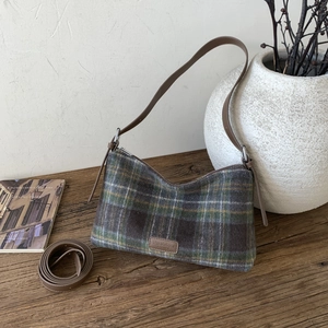 Détail d'un cabas vintage à carreaux avec lanières en cuir et étiquette Fashion sur bois