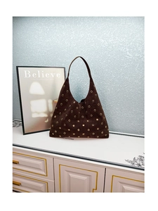 Detail of dark brown suede hobo bag featuring gold metal eyelet studs and large tote design