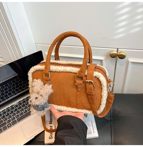 Détail d'un sac à main en daim marron avec bordure en peau de mouton et charme d'ours