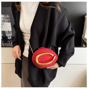 Detail of red lip-shaped acrylic crossbody bag with gold metal trim and chain strap