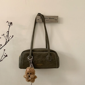Detail view of dark green leather shoulder bag with white contrast stitching and dog charm