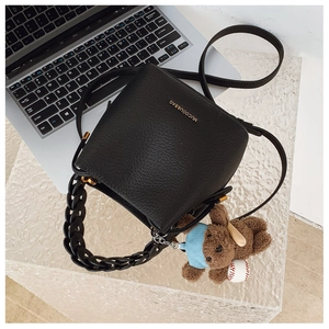 Detail of black pebbled leather bucket bag with gold logo and cute bear charm pendant