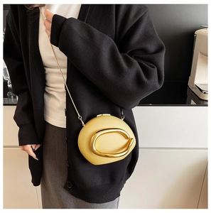 Detail view of bright yellow round acrylic clutch with golden metal ring on model