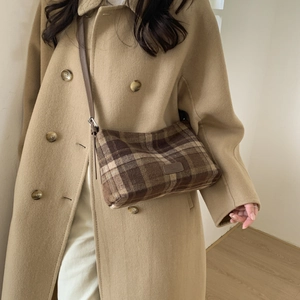 Détail du sac bandoulière à carreaux marron avec sangle en cuir et étiquette avant