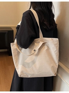 Minimalist beige tote bag with wide shoulder strap shown on a model for daily use
