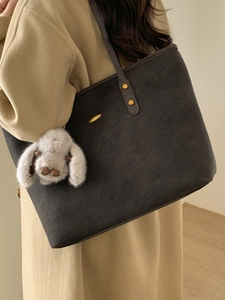 Large dark grey tote bag with brown straps and white bunny charm shown on shoulder